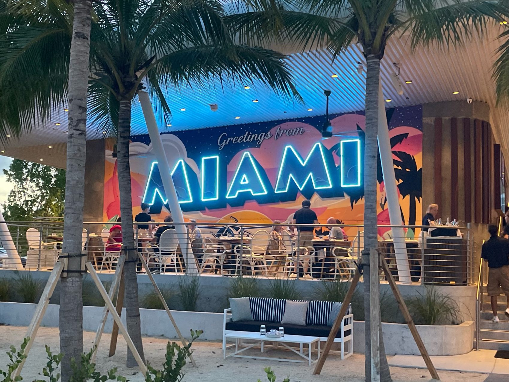 Bayshore Club seating area with Greetings From Miami mural